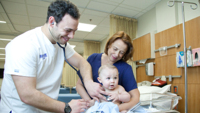 护理系学生和护理系老师用听诊器听婴儿的心脏